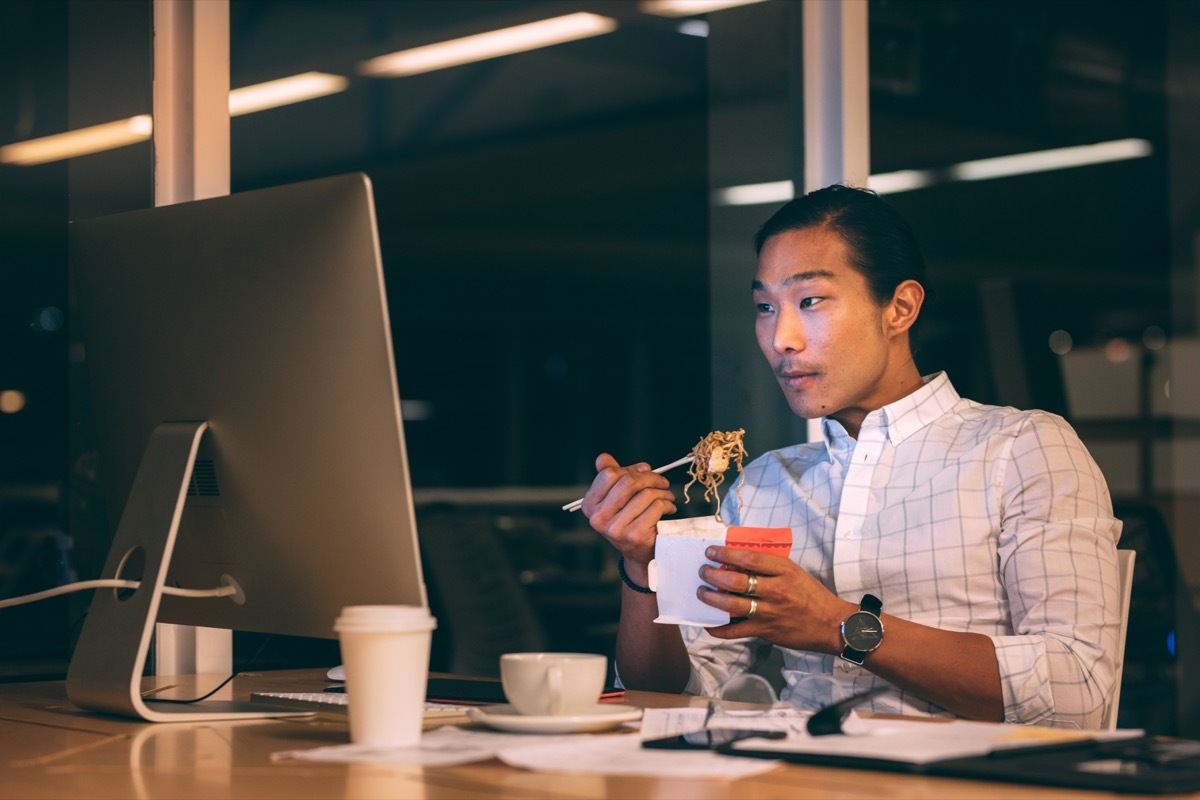 Man eating a late dinner at his desk