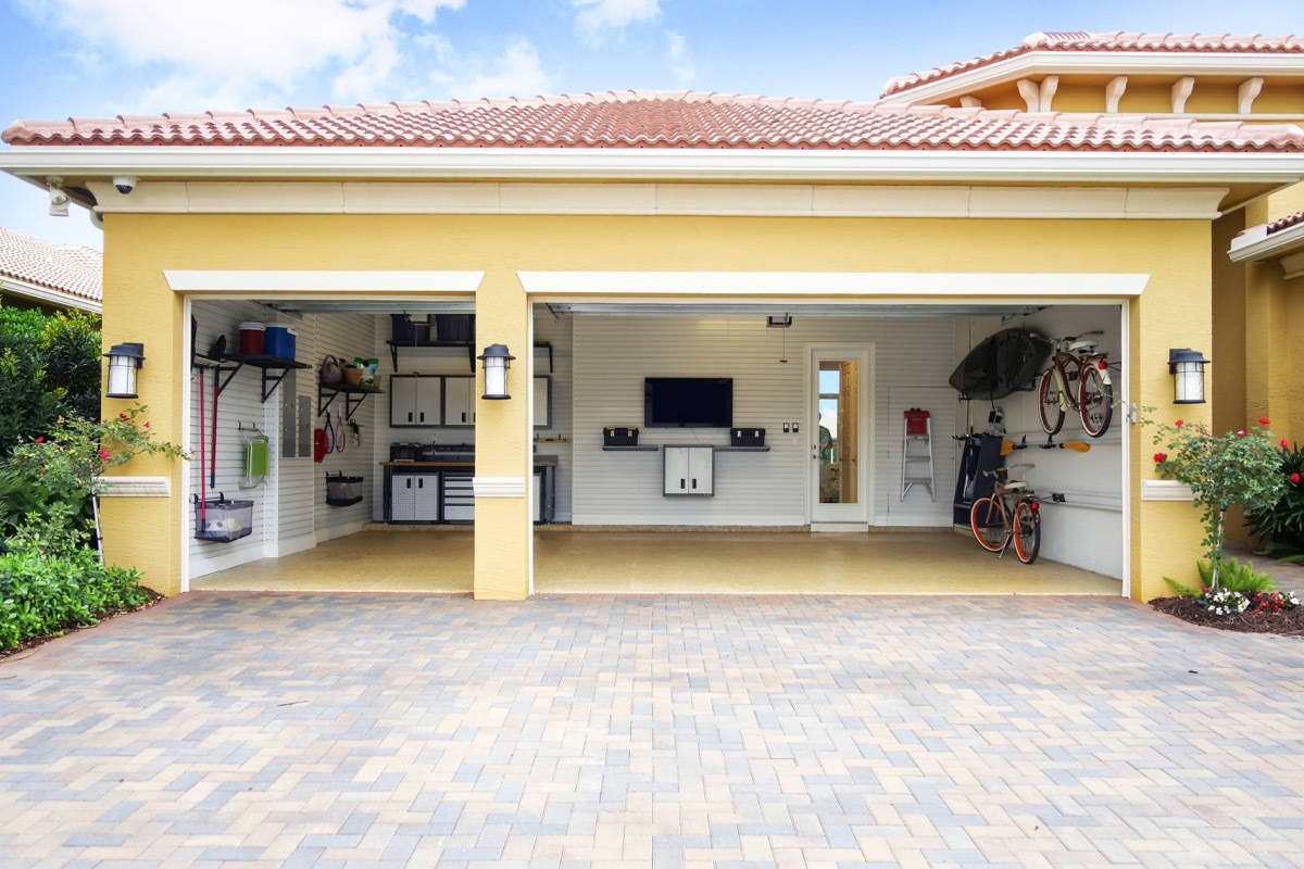 Three car garage attached to a home in a residential community. The garage is very neat and clean. It is well organized with shelves, bicycle racks,a work area and storage cabinets. It also has a flat screen tv on the wall. there are no cars in the garage. Daytime shot taken with a Canon 5D Mark 3 camera. rm