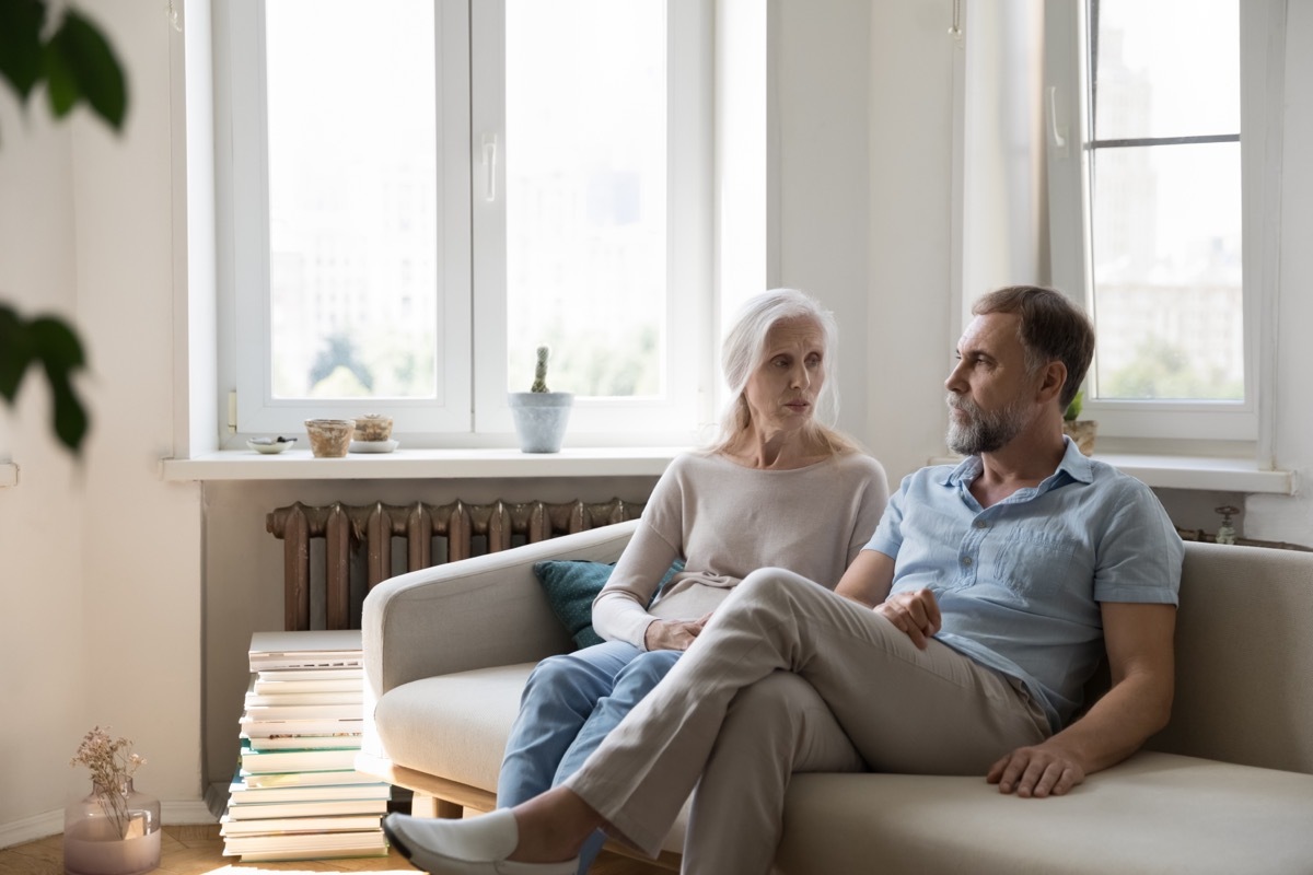 Upset elderly couple sitting on the cough together.