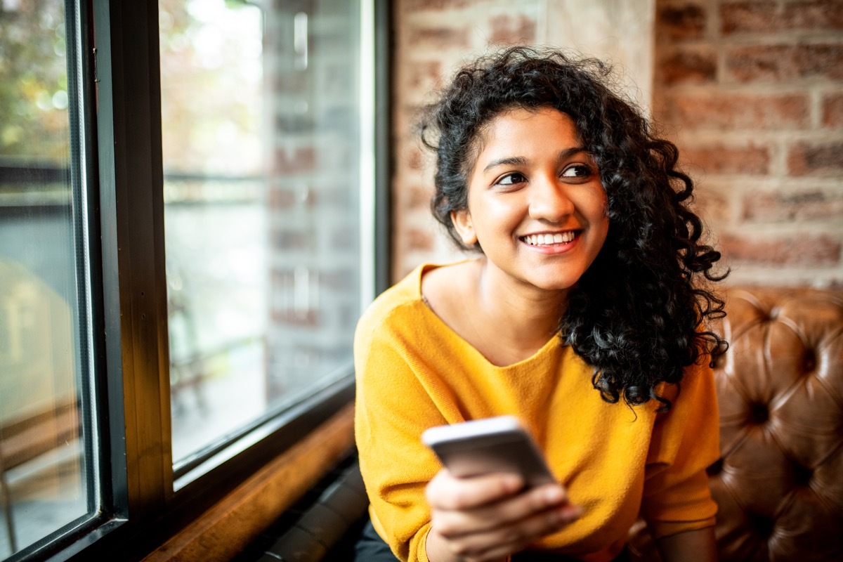 young woman smiling while using her phone