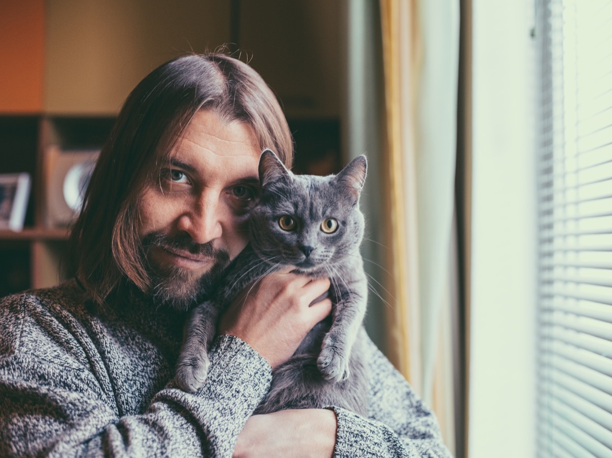 man hugging cute cat and looking at camera