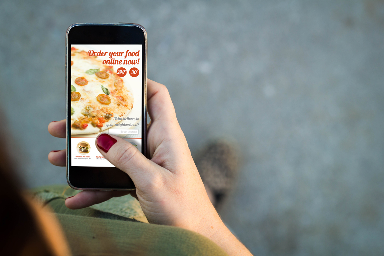 Top view of woman walking in the street using her mobile phone to order food online