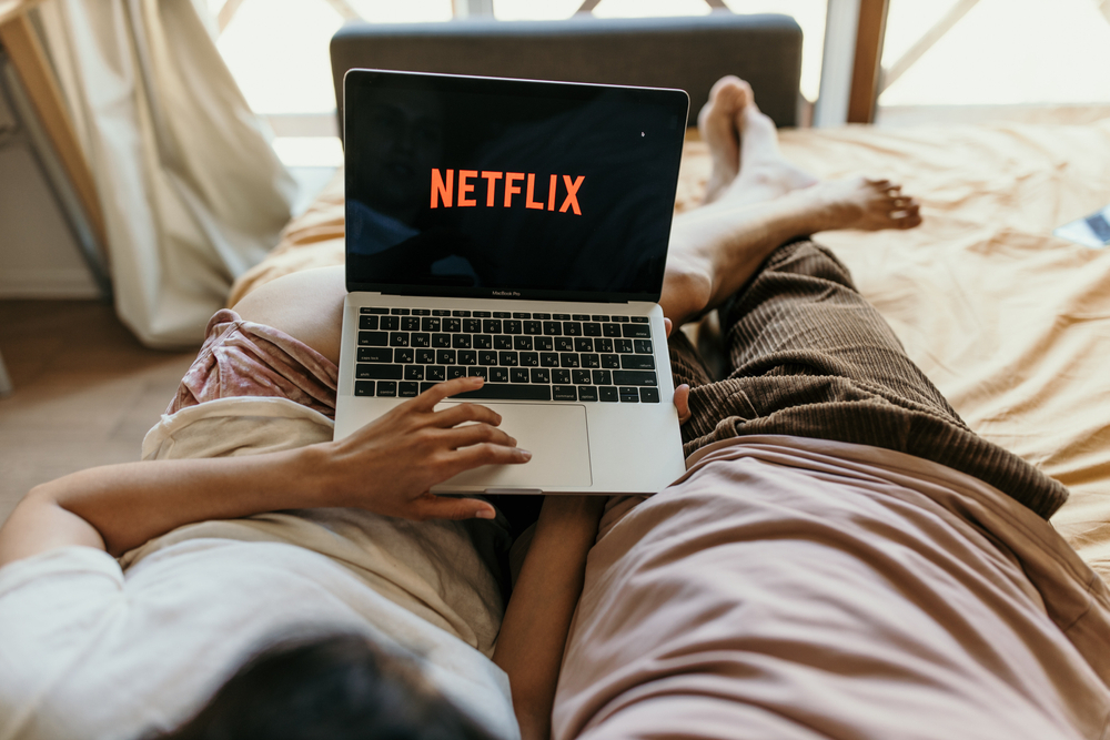 A couple lying in bed and watching Netflix on a laptop computer