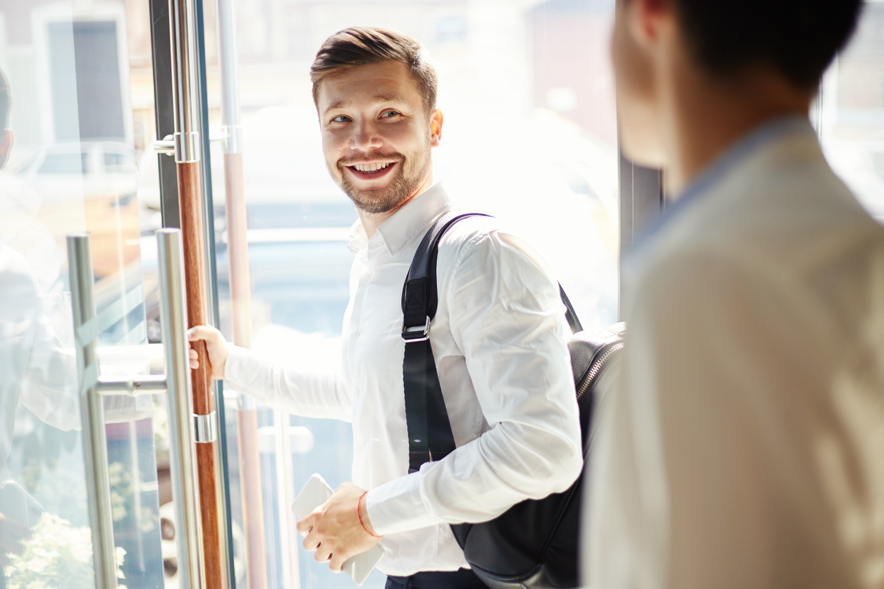 young man with backpack walking out of cafe door during conversation