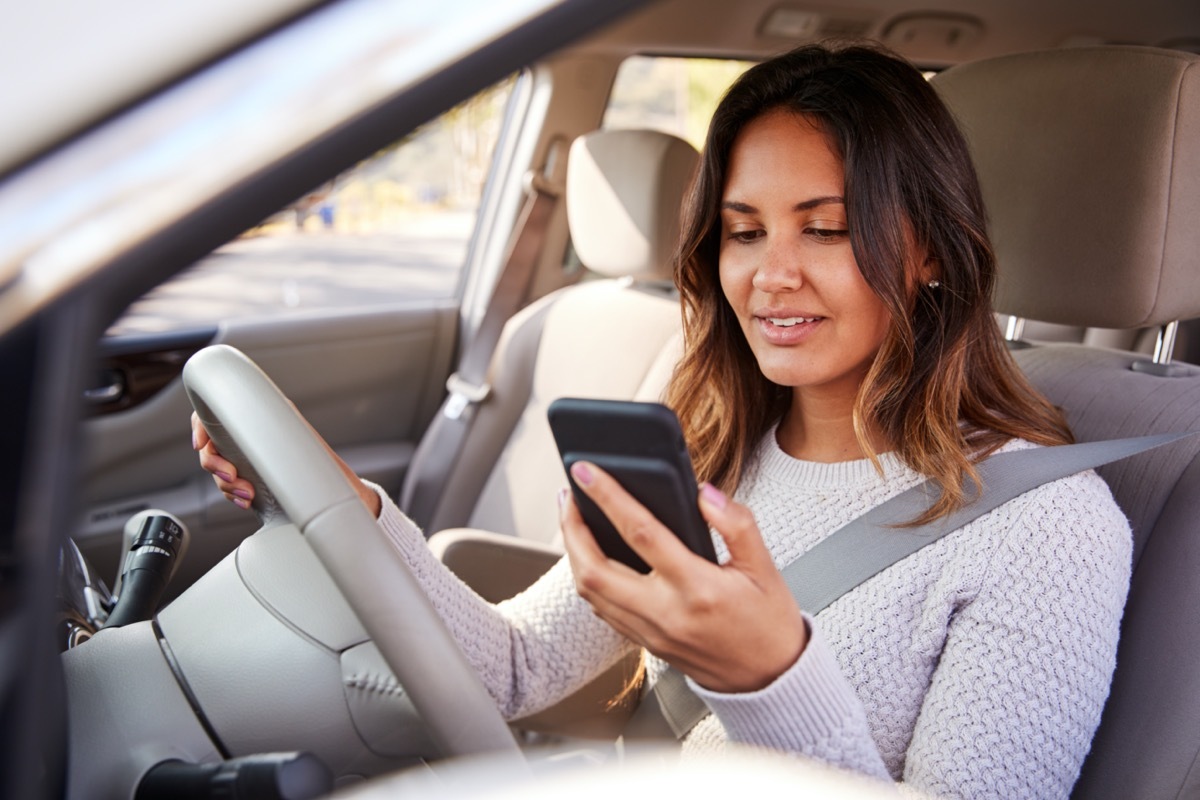 young woman looking at her phone in the car