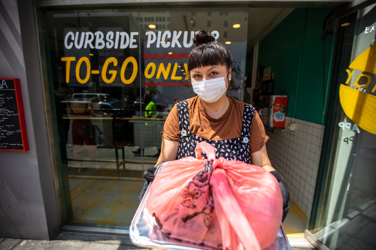 a young hispanic woman hands over a curbside order