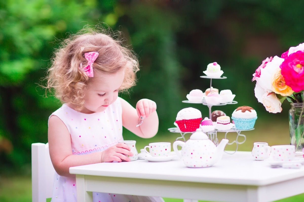 Little girl having a tea party outside