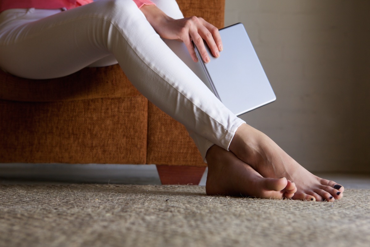 Close up portrait of woman feet on floor at home with digital tablet.